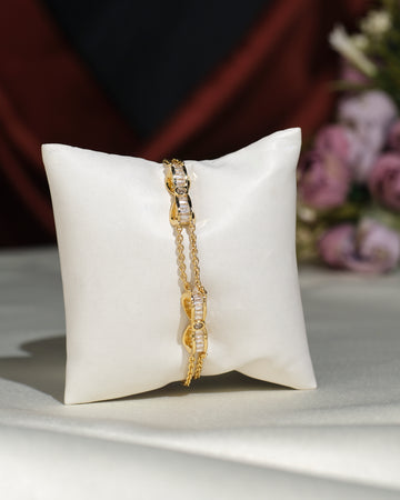 The Metallic CZ Pretty Bracelet by Chandrani Pearls India, featuring clear stone accents, rests on a white cushion with blurred purple flowers in the background, creating an elegant and charming display.