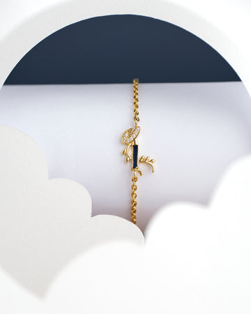 The Dainty Krishna Chain bracelet for kids by Chandrani Pearls India is displayed on a white and navy scalloped backdrop, featuring a blue gem with a leaf design.