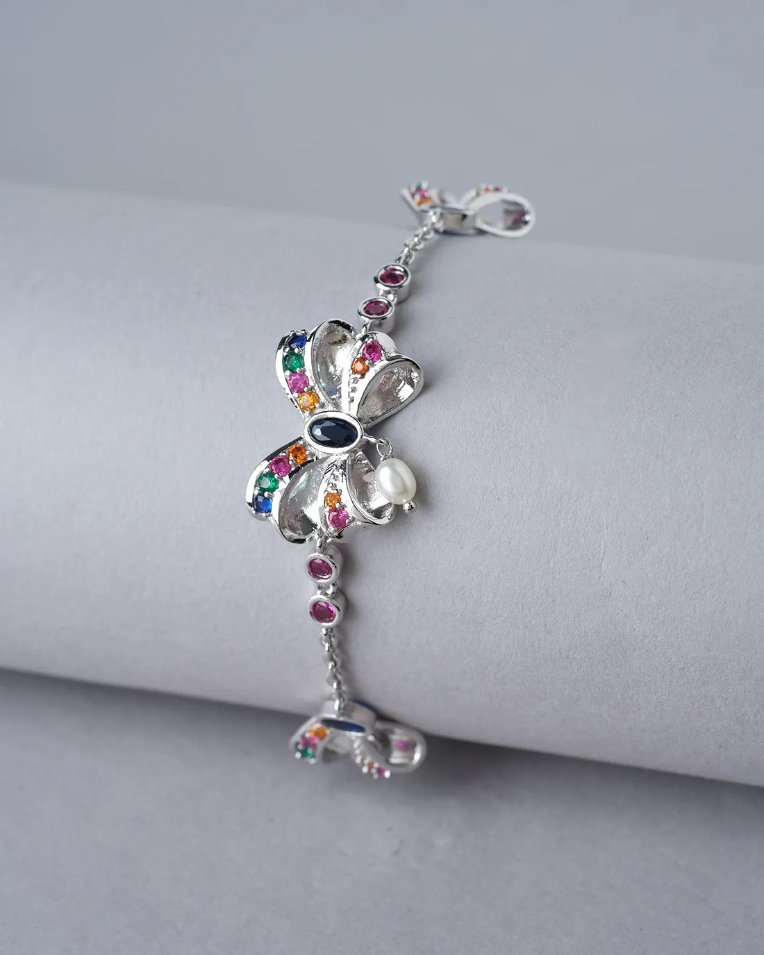 The Trendy Metallic CZ Pretty Bracelet by Chandrani Pearls India, shown on a white pillow against a burgundy backdrop, adds effortless charm to both casual outings and formal events.