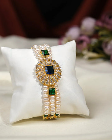 The Sanika Garnet Stone 3 Line Bracelet by Chandrani Pearls India features elegant pearls, striking stones, and sparkling crystals displayed on a white cushion—perfect for adding a touch of luxury to your everyday style.