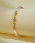 The Flory White 1 Line Pearl Bracelet by Chandrani Pearls India features gold, small floral designs, and clear stones for everyday elegance. Shown against a pale yellow background.