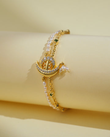 The Beautiful Boat 1 Line Pearl Bracelet by Chandrani Pearls India features pearl accents and a crescent charm with gemstones—an elegant accessory that brings sophisticated shine against a light cream backdrop.