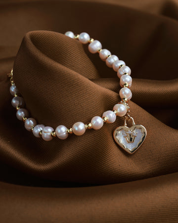 The Pearl Heart Whisper bracelet by Chandrani Pearls features gold beads and a heart pendant with a small deer, radiating subtle elegance and calm—a soft statement of beauty inspired by moonlight.