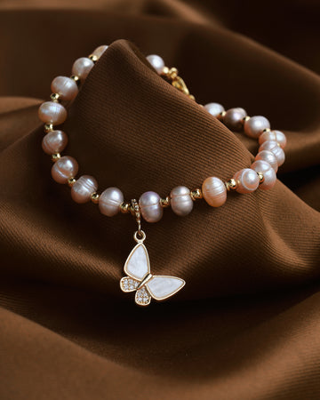 The Butterfly Shell Shine bracelet by Chandrani Pearls features genuine mother-of-pearl and a gold butterfly charm, exuding natural glow and subtle luxury to complement any outfit.