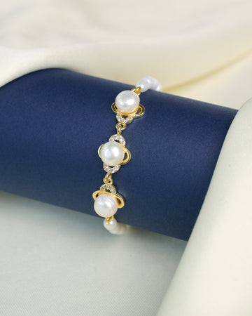 The Chandrani Pearls Refined Pearl Bracelet with Brilliant CZ Stones showcases round white pearls and sparkling cubic zirconia, elegantly displayed on a navy cylinder against a cream fabric background.