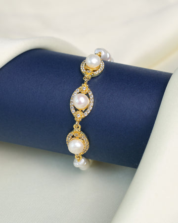 The Chandrani Pearls Delicate Pearl Bracelet with Cubic Zirconia Sparkle is shown on a navy blue cylindrical holder, accented by cream-colored fabric.