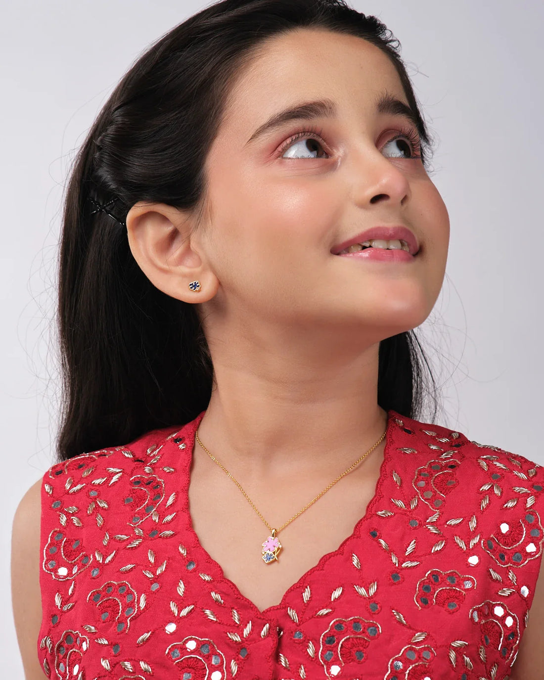 The Floral Enamel Pendant Sets by Chandrani Pearls India include a gold necklace with a pink flower and black clover pendant, paired with black clover stud earrings, displayed against a wizard silhouette and star background.
