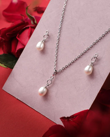 The Perry Pear 925 Silver White Pendant Set by Chandrani Pearls India includes a chain necklace and matching earrings with white pearl pendants, beautifully displayed on a pink card with red roses—ideal for any occasion.