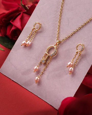 The Trio Threads 925 Silver Pendant Set by Chandrani Pearls India, paired with matching earrings featuring pearl and crystal accents, is displayed on a pink card amid red roses, showcasing refined craftsmanship.
