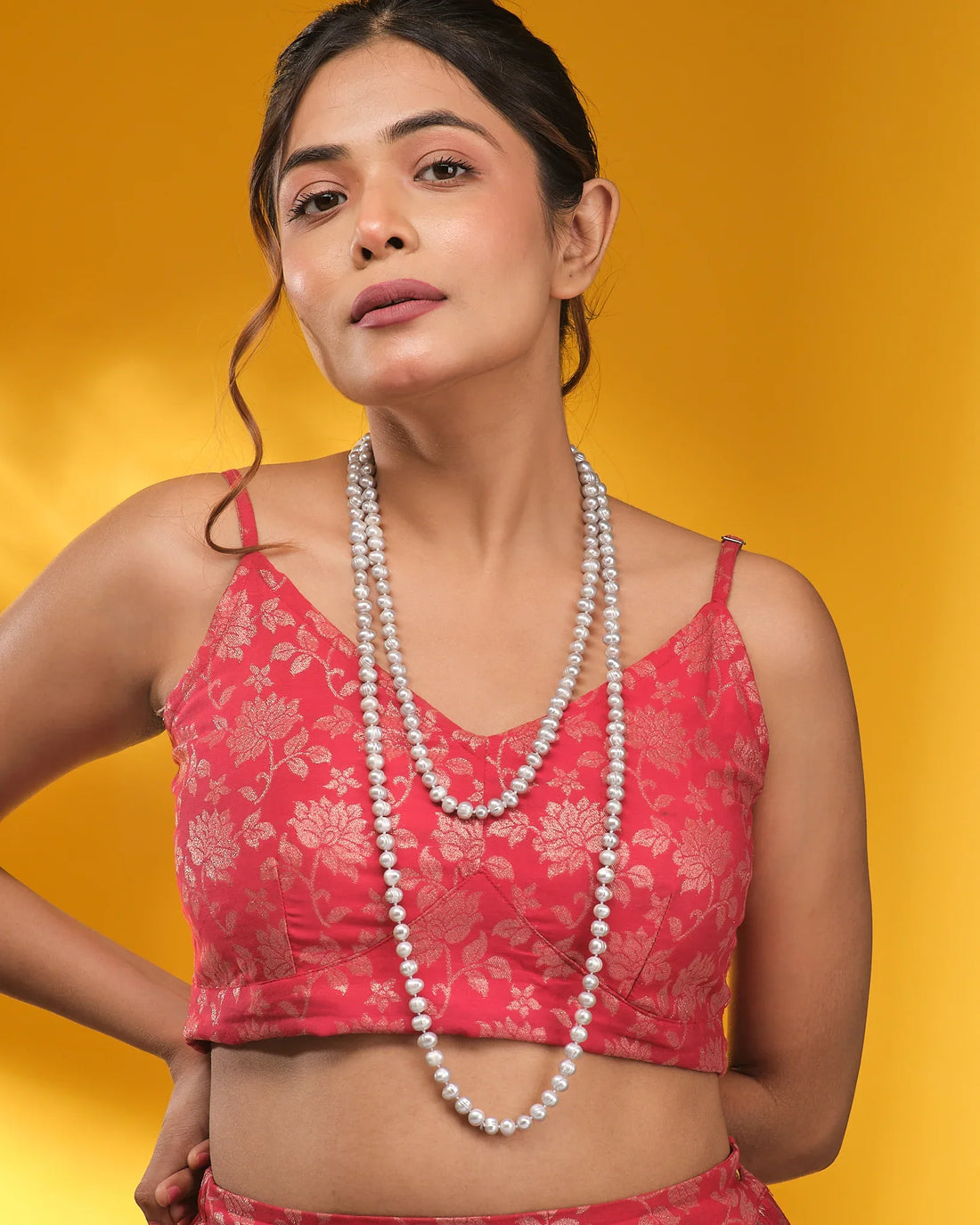 The Knotted Pearl Necklace by Chandrani Pearls is showcased on a dark blue velvet bust, with soft cream fabric elegantly draped in the background.