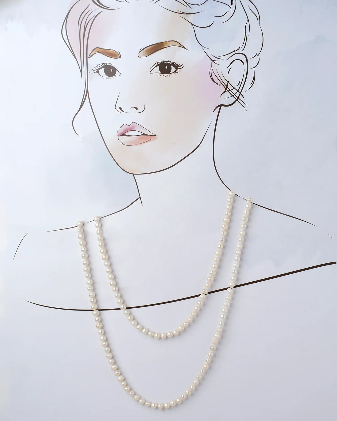 The Heavenly Pearl Necklace by Chandrani Pearls features elegant white pearls arranged in a circular form on a purple and pink background with delicate white flowers in the foreground.