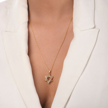 A person wearing a white blazer showcases The Star of David Pendant from Chandrani Pearls, a symbol of unbreakable ties.