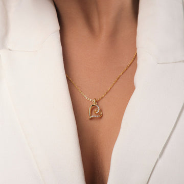 A person wearing a white blazer with Chandrani Pearls' Classic Love Pendant—a gold heart-shaped necklace outlined with sparkling Cubic Zirconia stones.