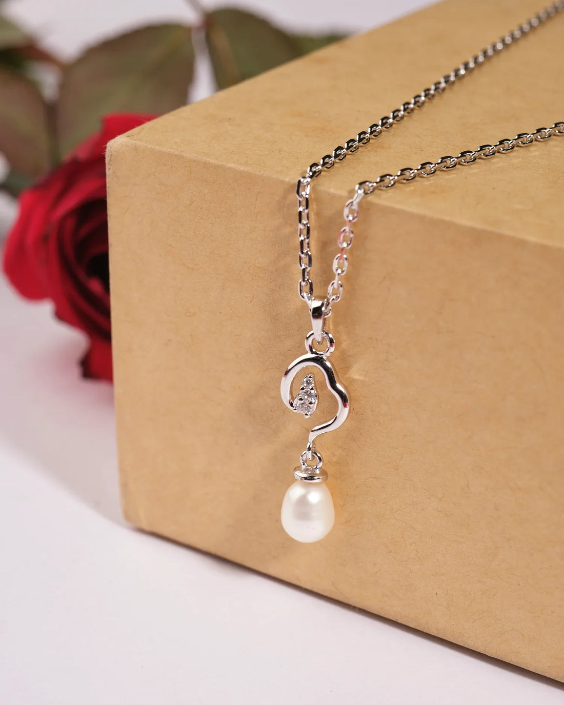 Chandrani Pearls India's Shining String 925 Silver Pendants feature a pearl and crystal accent, elegantly displayed on a light pink card with red roses—ideal for formal or casual occasions.