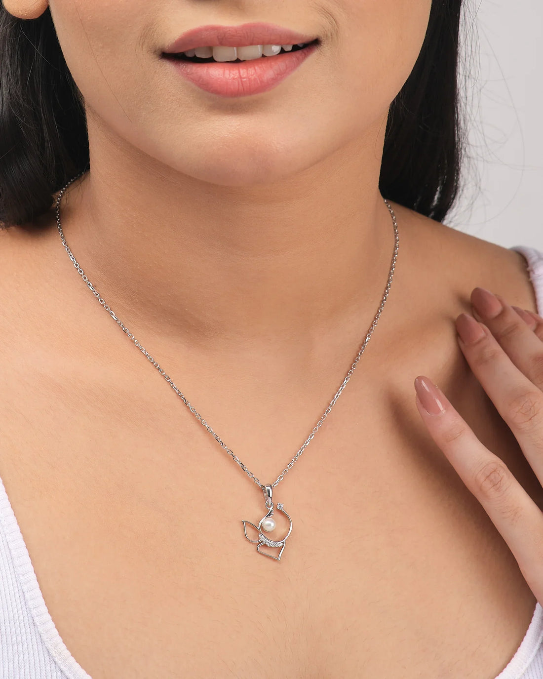 The Demifine Radiance Pendant by Chandrani Pearls features a delicate 925 silver design with CZ and pearl, beautifully displayed on a white surface with a purple ribbon.