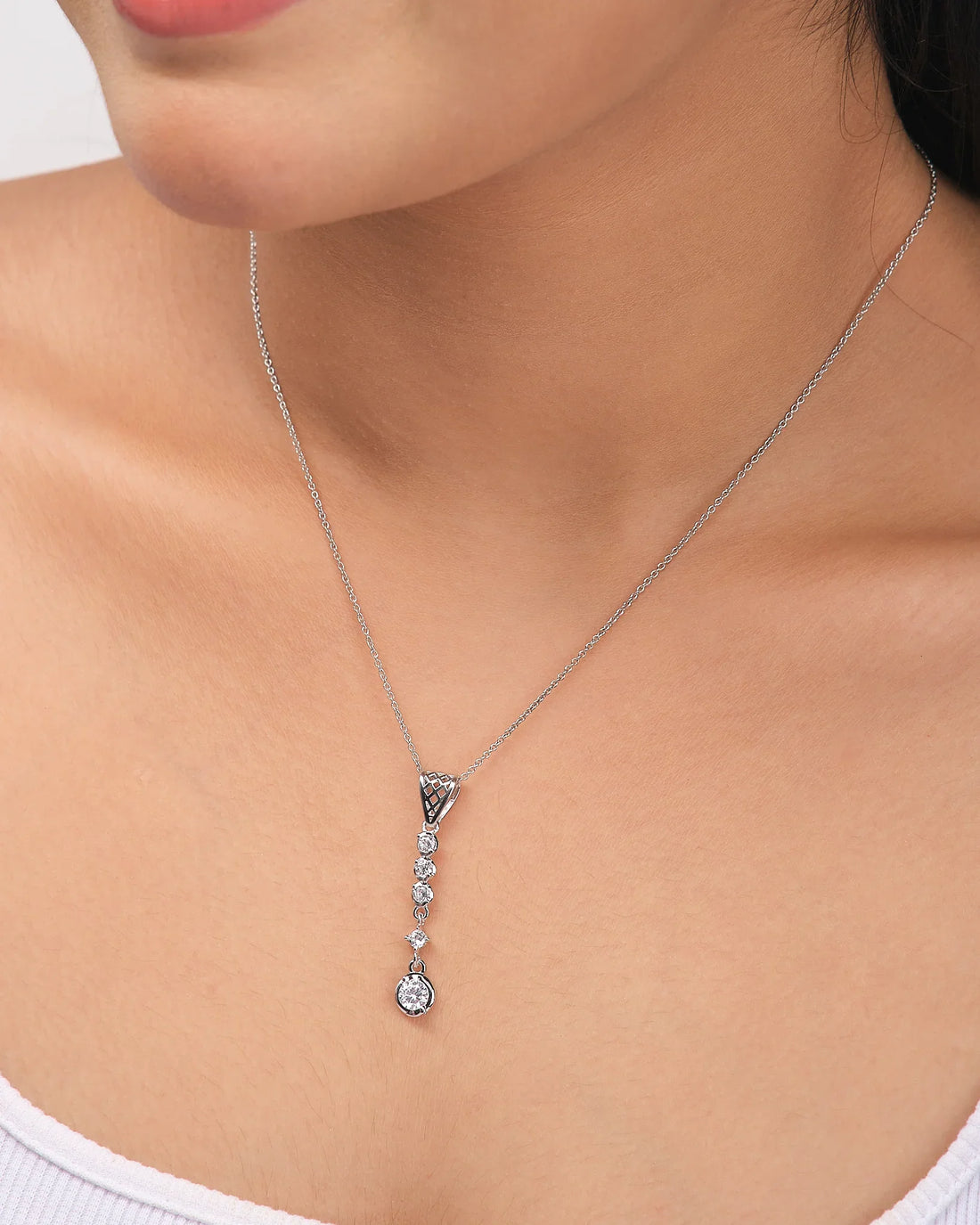 The Demifine Grace Pendant 925 Silver with CZ Sparkle by Chandrani Pearls features a row of clear gemstones and a round crystal, shown on a white background with a purple ribbon—an elegant choice for any occasion.