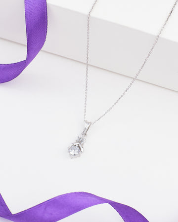 The Chandrani Pearls Classic Demifine Silver Pendant with Dazzling CZ Accent is displayed on a white surface next to a purple ribbon.
