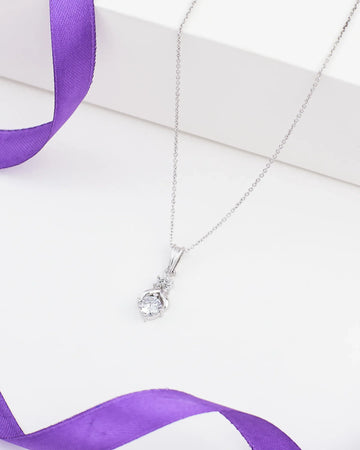 The Chandrani Pearls Classic Demifine Silver Pendant with Dazzling CZ Accent is displayed on a white surface next to a purple ribbon.