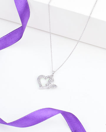 The Chandrani Pearls Heart-Butterfly Demifine Silver CZ Pendant features a heart-butterfly shape with sparkling crystals and leaf detail, shown on a white surface with a purple ribbon.