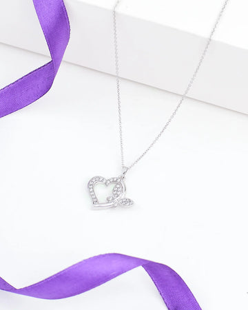 The Chandrani Pearls Heart-Butterfly Demifine Silver CZ Pendant features a heart-butterfly shape with sparkling crystals and leaf detail, shown on a white surface with a purple ribbon.