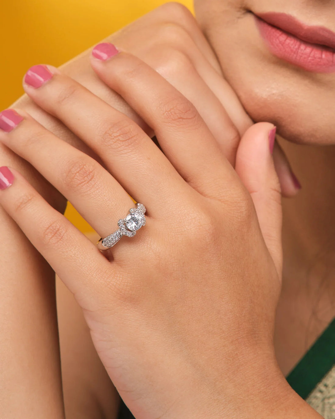 The Solitaire Silver Ring Sleek and Modern by Chandrani Pearls features a large round central gemstone and a band of smaller stones, elegantly showcased on a brown fabric background.