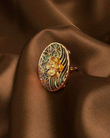 An elegant, iridescent ring by Chandrani Pearls dazzles with mother-of-pearl beauty, floral accents, and geometric design, showcased on rich brown satin fabric.