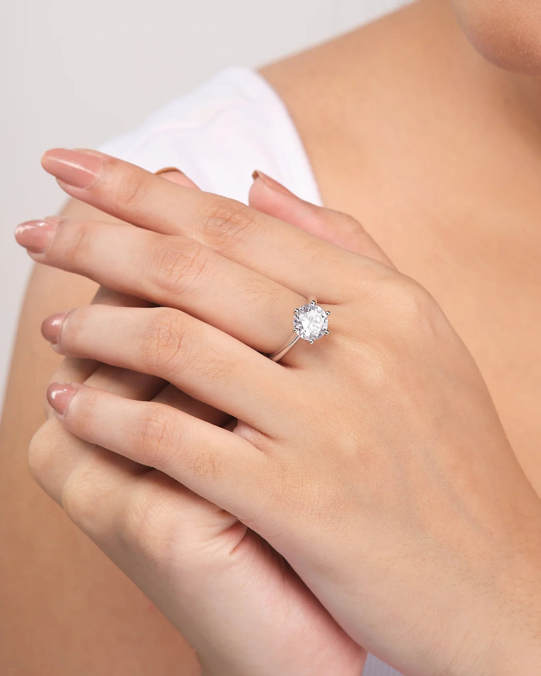 The Elegant Solitaire CZ Ring in Demifine Sterling Silver by Chandrani Pearls is showcased on a white surface with a purple ribbon in the background.