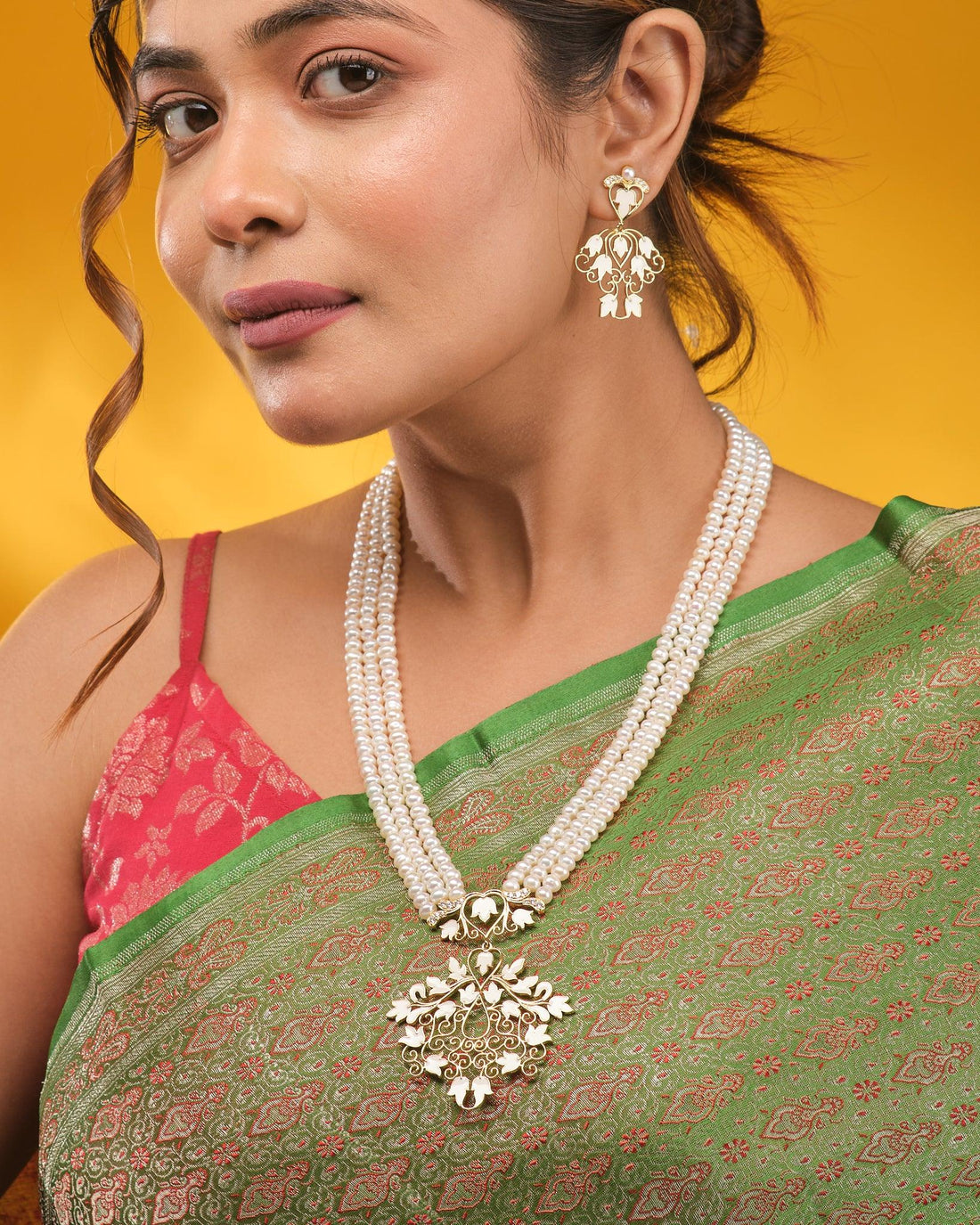 The Noor Majesty Pearl CZ Necklace Set by Chandrani Pearls features a pearls necklace with a gold and white floral pendant and matching earrings accented with CZ halos, elegantly displayed on brown fabric.