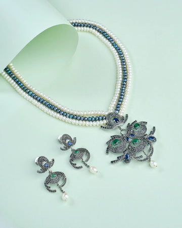 The Stylish pearl set by Chandrani Pearls, crafted to complement both ethnic and western wear, features a black-and-white beaded necklace with ornate pendant and matching earrings—perfect for elegant occasions.