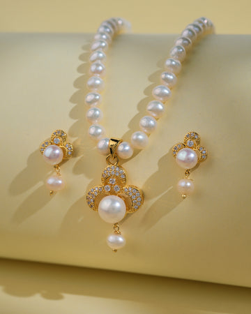 The Trendy Pearl Necklace Sets by Chandrani Pearls India feature a pearl necklace with gold and diamond pendant and matching pearl and gold earrings on a pale yellow background, blending classic pearls with modern design for timeless elegance.