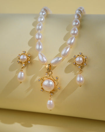 The Trendy Pearl Necklace Sets by Chandrani Pearls India feature elegant teardrop pearls and sparkling stones in a refined necklace and earrings set, perfect for the modern woman, shown on a pale yellow background.