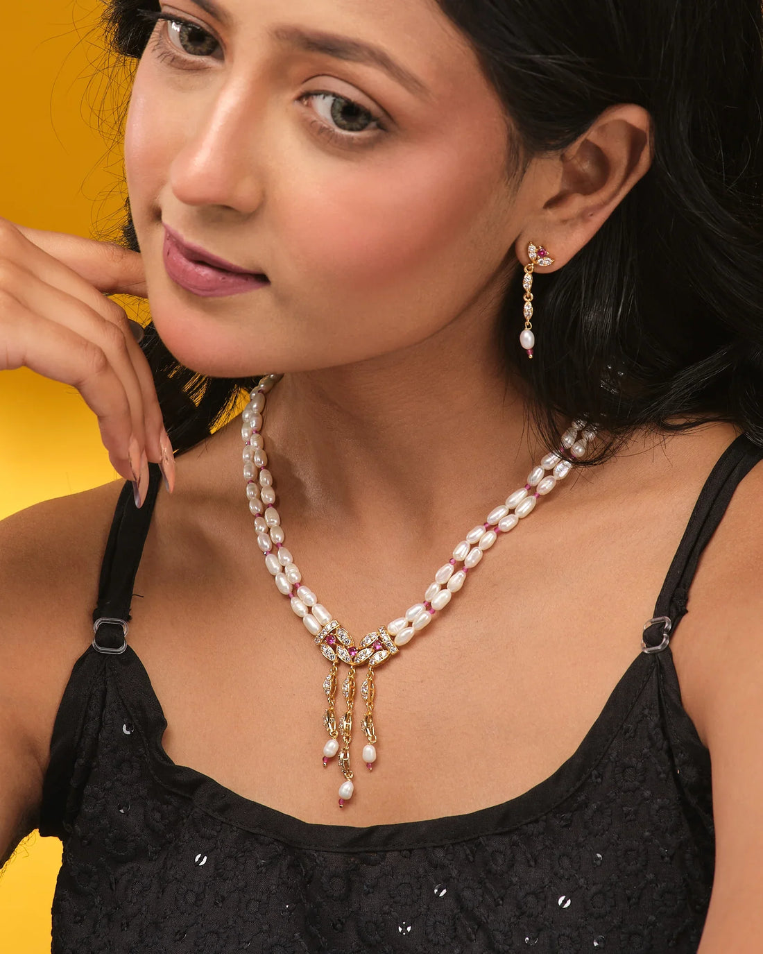 The Chandrani Pearls Vintage-Inspired Beads & Pearl & Crystal Set adds Hollywood charm with three dangling pendants and matching drop earrings, displayed elegantly on a beige surface.