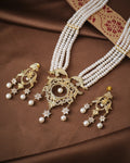 The Graceful Queen Pearl CZ Necklace Set by Chandrani Pearls features shimmering pearls, CZ work, a multi-strand necklace, and matching star-accented earrings with intricate designs displayed on brown fabric.