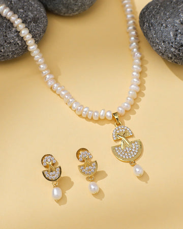 The Modern Necklace Pearl Set by Chandrani Pearls features a gold and CZ crystal pendant with matching earrings, beautifully displayed on yellow with black stones—ideal for the stylish woman.