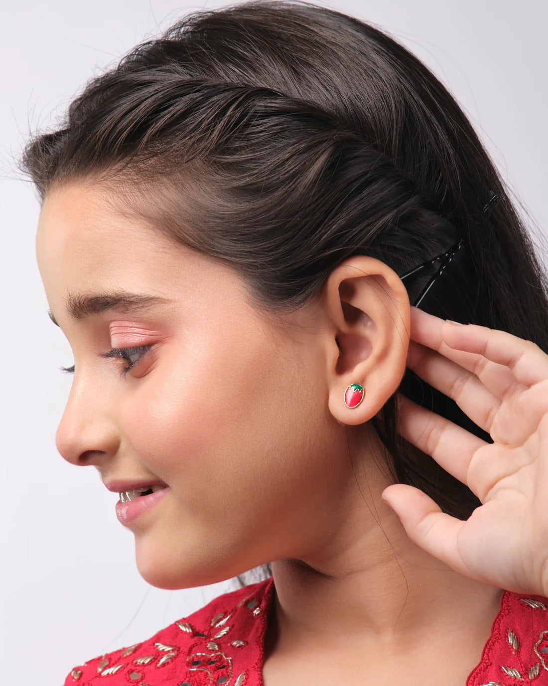 The Stawberry Stud Earring by Chandrani Pearls India features red strawberry-shaped earrings on a star-shaped background with a silhouette of a cat holding an umbrella.