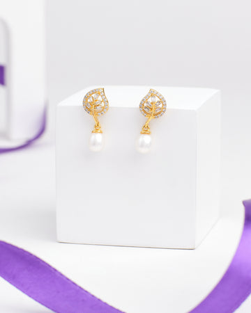 Sparkling Duo Silver Earrings by Chandrani Pearls feature a leaf-shaped design with clear stones and dangling pearls, radiating moonlight charm—an exquisite choice for lovers of delicate jewelry. Displayed on a white cube with a purple ribbon nearby.