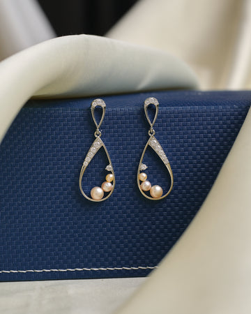 Chandrani Pearls' Sophisticated pearl drops, accented by dazzling CZ crystals, are showcased on a textured blue box with cream fabric—ideal for adding evening elegance to any outfit.