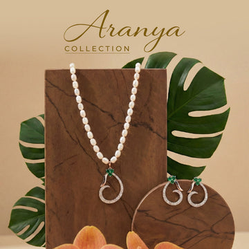 A woman in a white sleeveless top wears pearl jewelry, including a necklace and earrings, and smiles at the camera. Text reads "Aranya Collection." A green leaf is in the background.