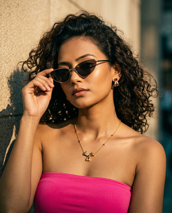 Woman wearing sunglasses and a pink top against a neutral background