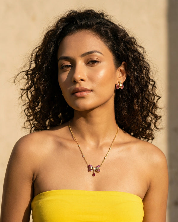 Woman wearing a yellow top and necklace with a neutral background