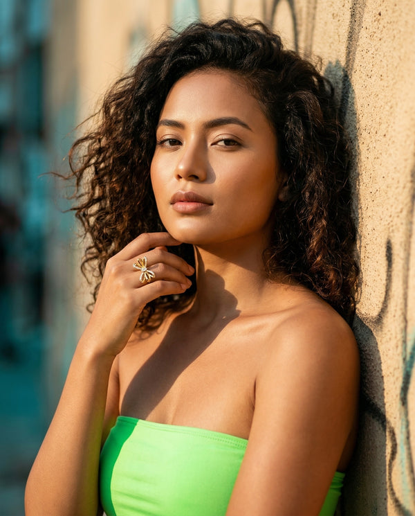 Woman in a green strapless top leaning against a textured wall.