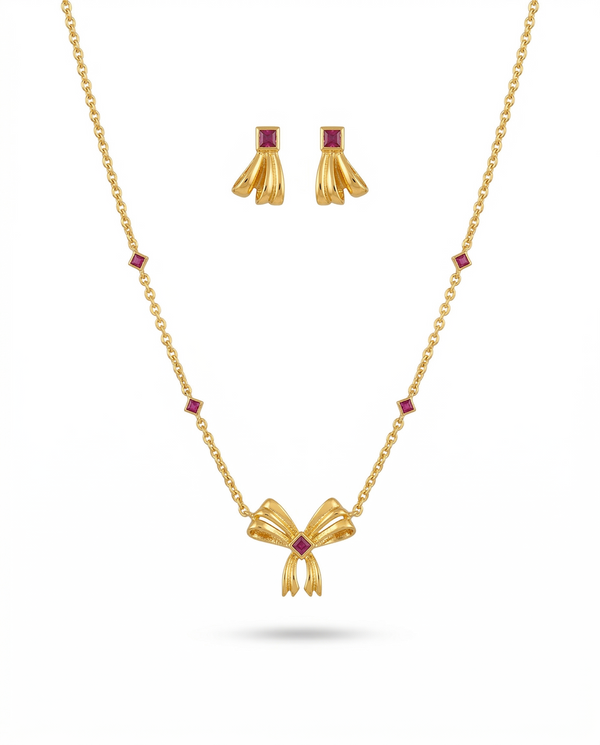 Gold necklace with bow pendant and matching earrings on a white background