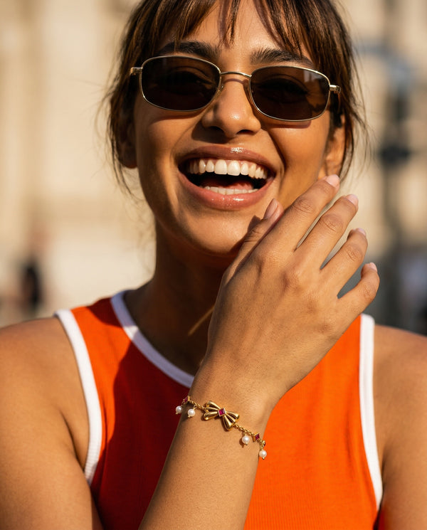 Woman wearing sunglasses and an orange top with a blurred background