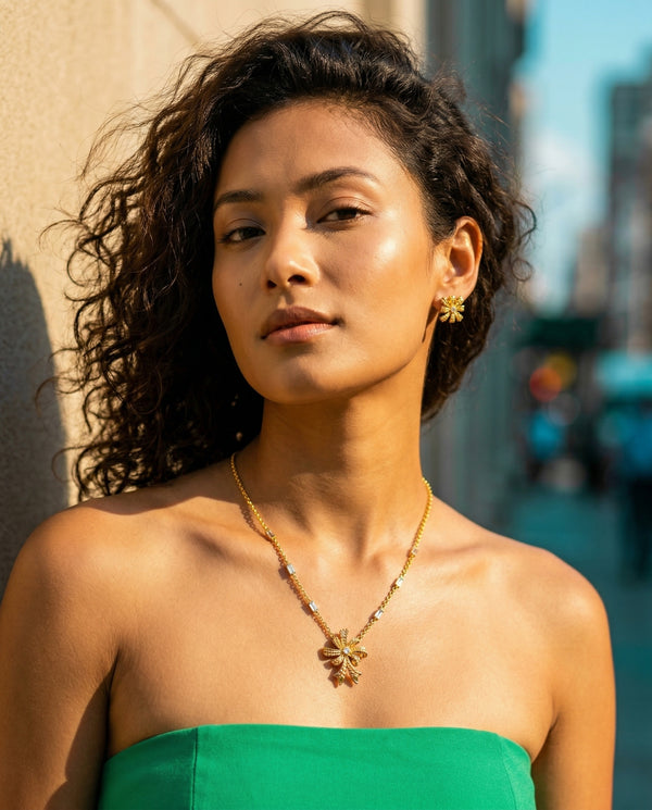 Woman wearing a gold necklace and green top outdoors
