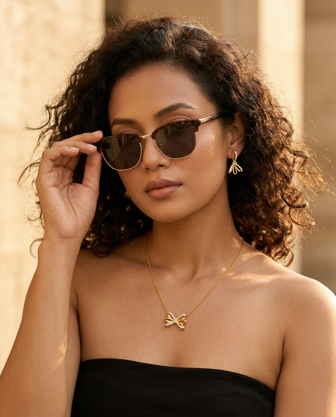 Gold necklace and earrings with bow design on a white background