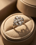 Silver ring with diamonds on a beige cushion in an open jewelry box