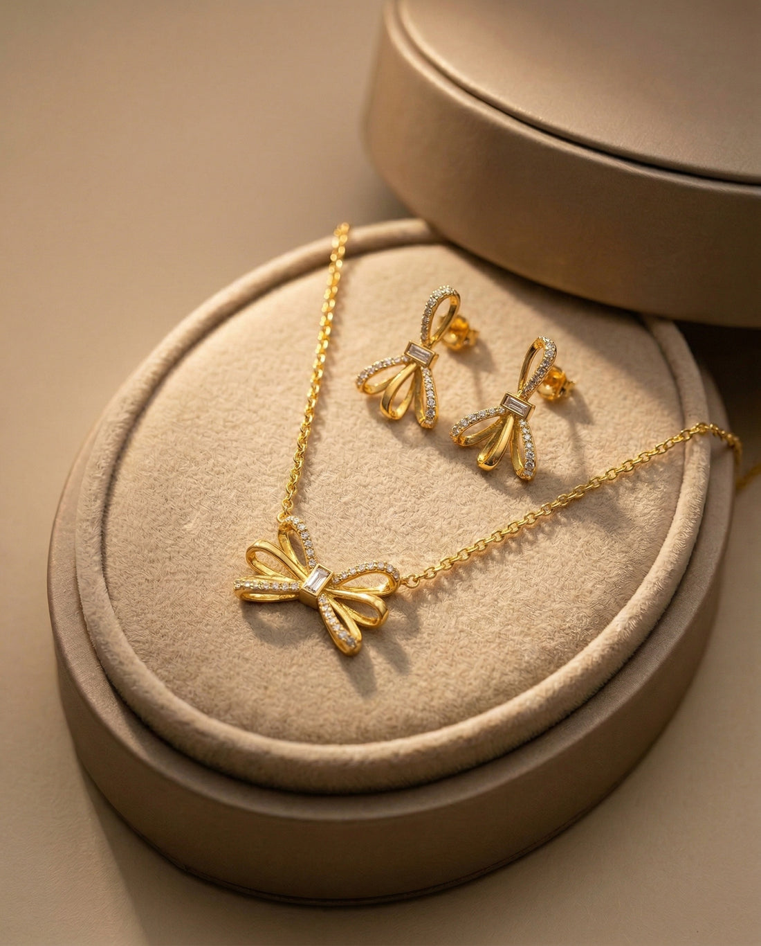 Gold necklace and earrings with bow design on a white background
