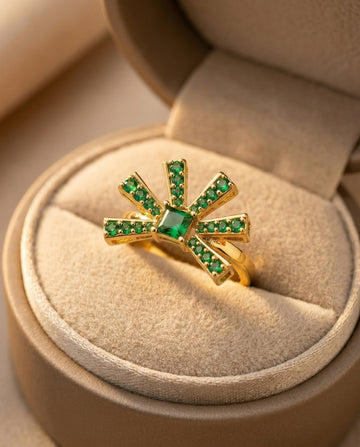 Gold ring with green gemstones on a beige jewelry box
