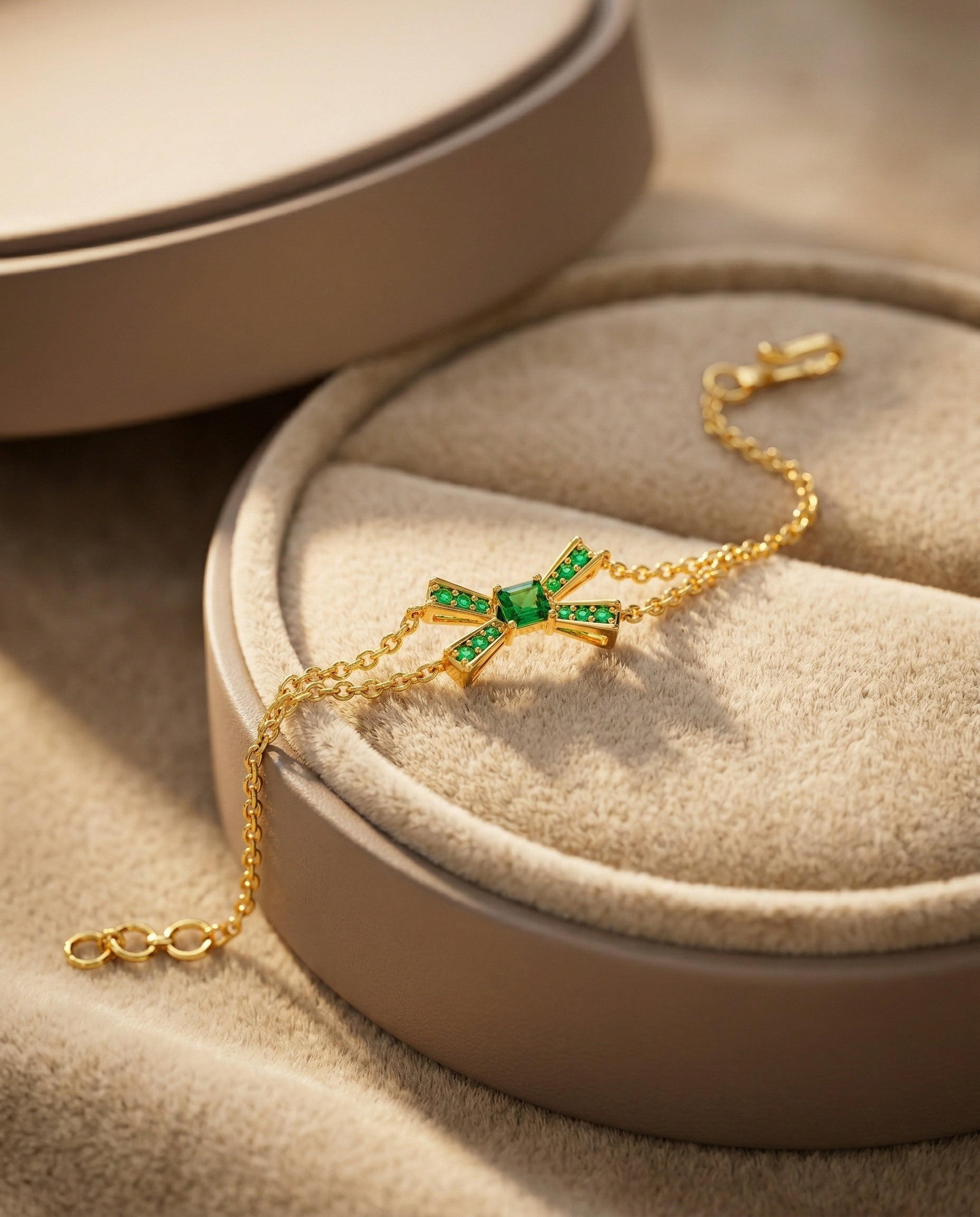 Gold bracelet with green gemstones on a beige jewelry box
