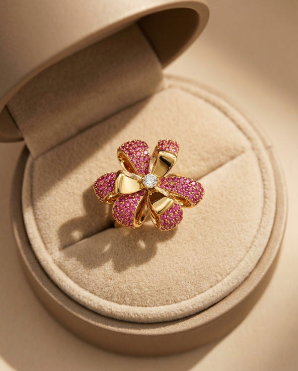 Gold and pink gemstone flower-shaped ring in a beige jewelry box